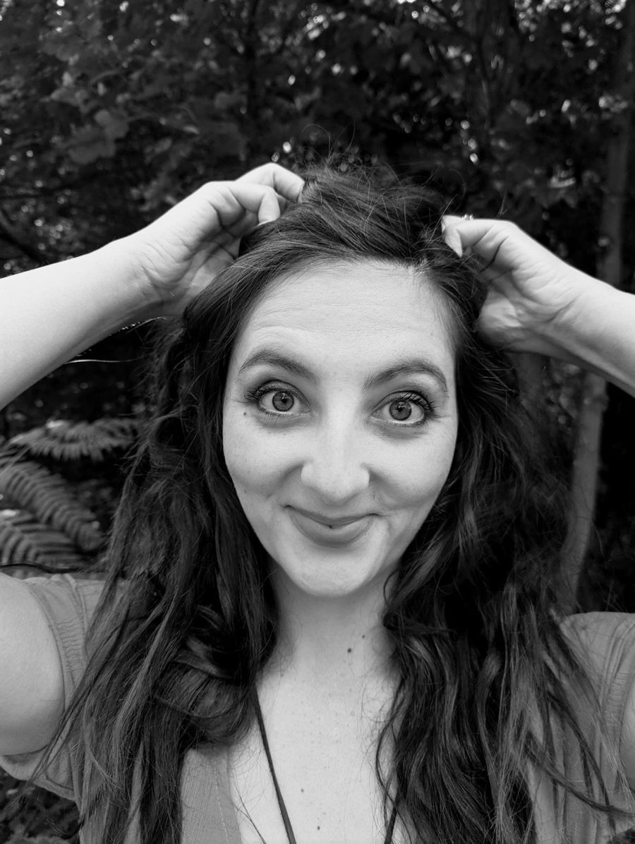 Ria Peake smiling, in black and white, among trees